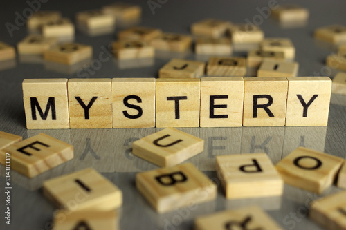 the word mystery is made up of square wooden letters on a gray background. Concept for mysteries, suspense and crime thriller genre. photo