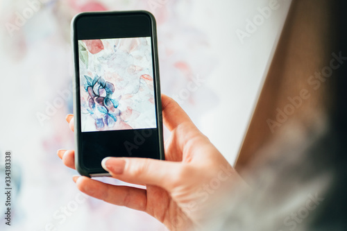 Contemporary art. Virtual gallery. Hands of woman taking picture of abstract floral watercolor painting