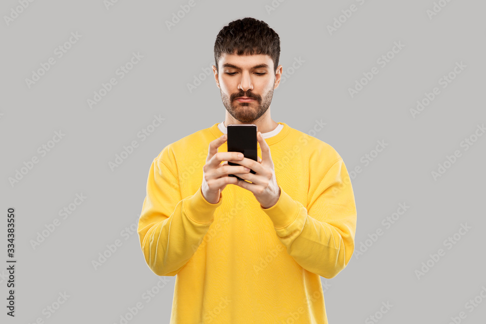 technology, communication and people concept - young man with smartphone over grey background technology, communication and people concept - young man with smartphone over grey background