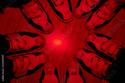 Feet of five friends in bowling shoes standing close to one another on the floor