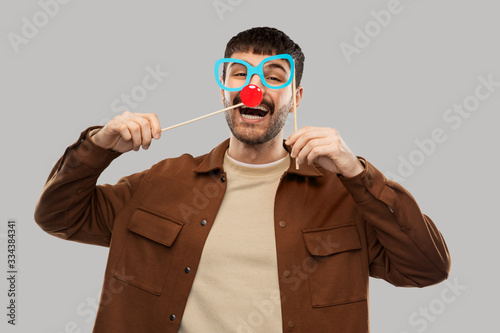 Платно party props, photo booth and people concept - happy smiling young man with paper