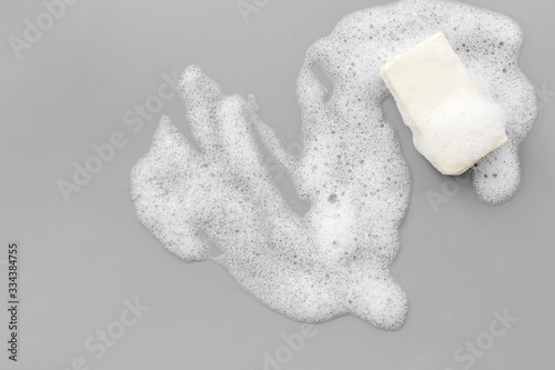 Foto Soap bar with bubbles on grey background top-down