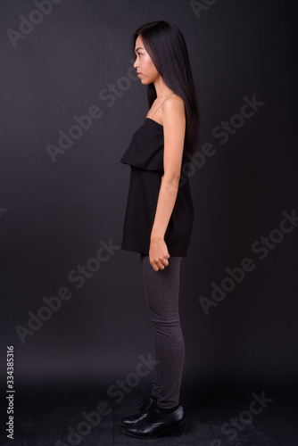 Full body shot profile view of young beautiful Asian woman