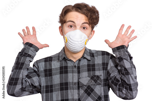 Concept of coronavirus quarantine. Scared Child wearing medical protective face mask. COVID-19 - home isolation. Shocked teen boy isolated on white background. Teenager looks at camera in amazement.