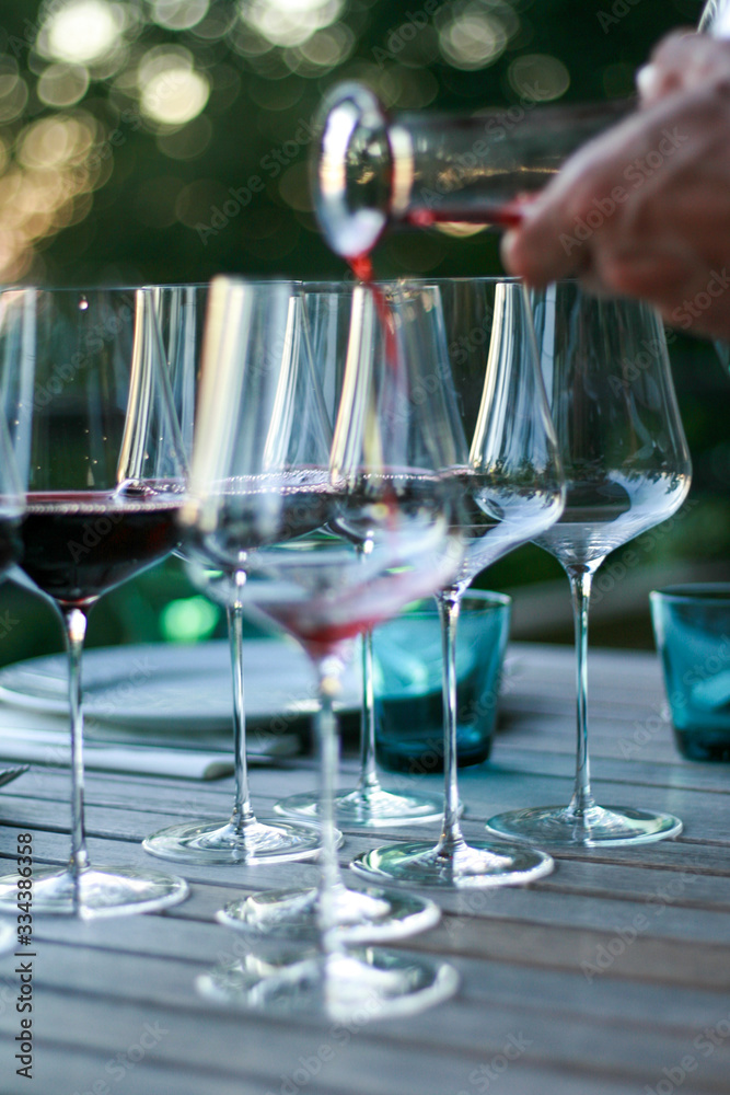 Fototapeta premium Man pouring red wine into glasses.