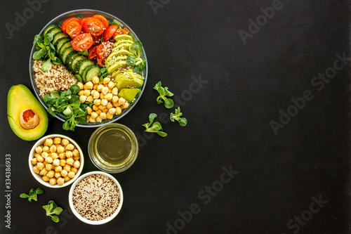 Vegan bowl. Avocado, quinoa, tomato, spinach and chickpeas vegetables salad on black table top-down copy space