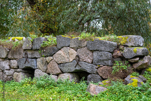 Old overgrown rock wall with forged loops as reinforcement