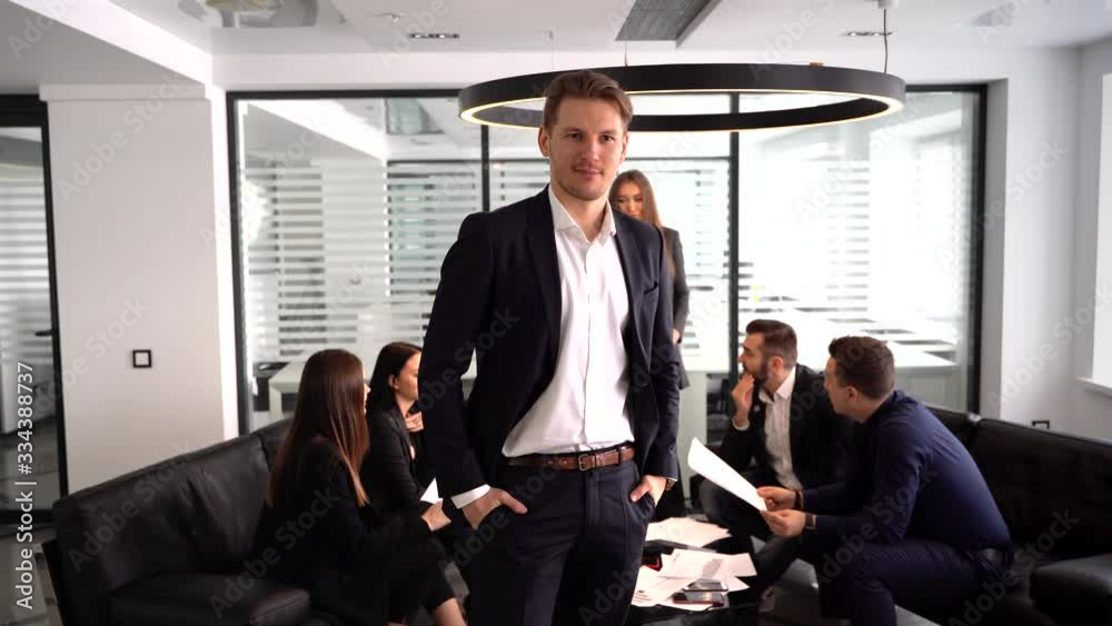 successful manager looking at camera on the background of talking people
