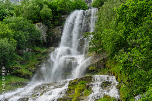 Beautiful waterfall surrounded by lush green vegetation © Magnus