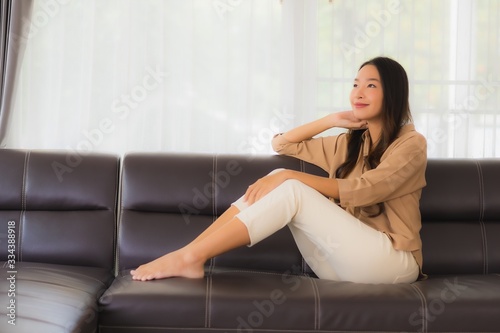 Portrait beautiful young asian woman happy smile relax on sofa in living room © siraphol