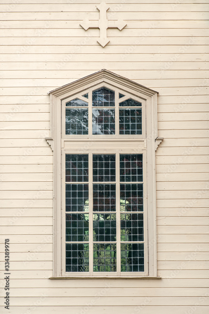 Large window on a pale wooden church wall