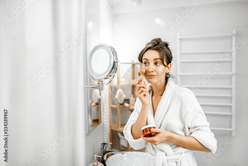 Young woman doing face massage during hygiene procedures in the bathroom
