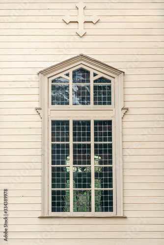 Large window on a pale wooden church wall