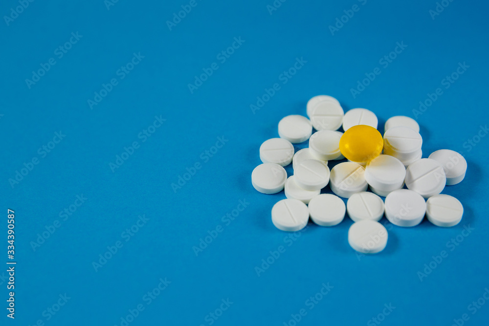 heap of white pills and one yellow, on a blue background