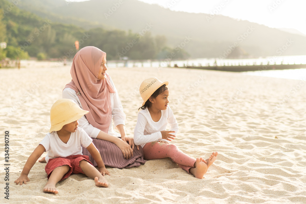 Asian kids having leisure time with their mother at the beach.