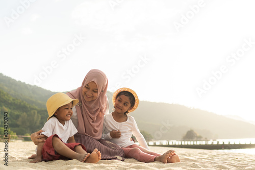 Asian kids having leisure time with their mother at the beach.