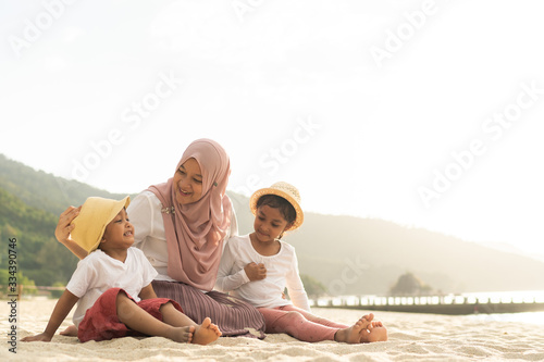 Asian kids having leisure time with their mother at the beach.