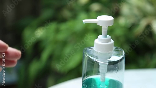 man hands that washing by alcohol sanitizer gel in a bottle for protecting infection from a Covid-19 virus and other viruses with green nature background.