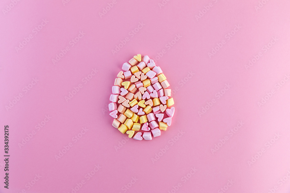 Single multicolored easter egg made of small marshmallows hearts on a pink background. Concept. Single multicolored easter egg made of small marshmallows hearts on a pink background. Concept.