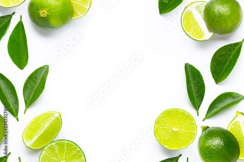 Frame made of fresh limes with green leaves on white background.