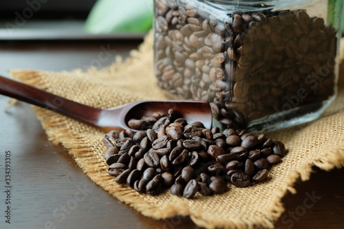 深入りコーヒー豆とガラス瓶。roasted coffee beans with a glass jar on a old wooden table