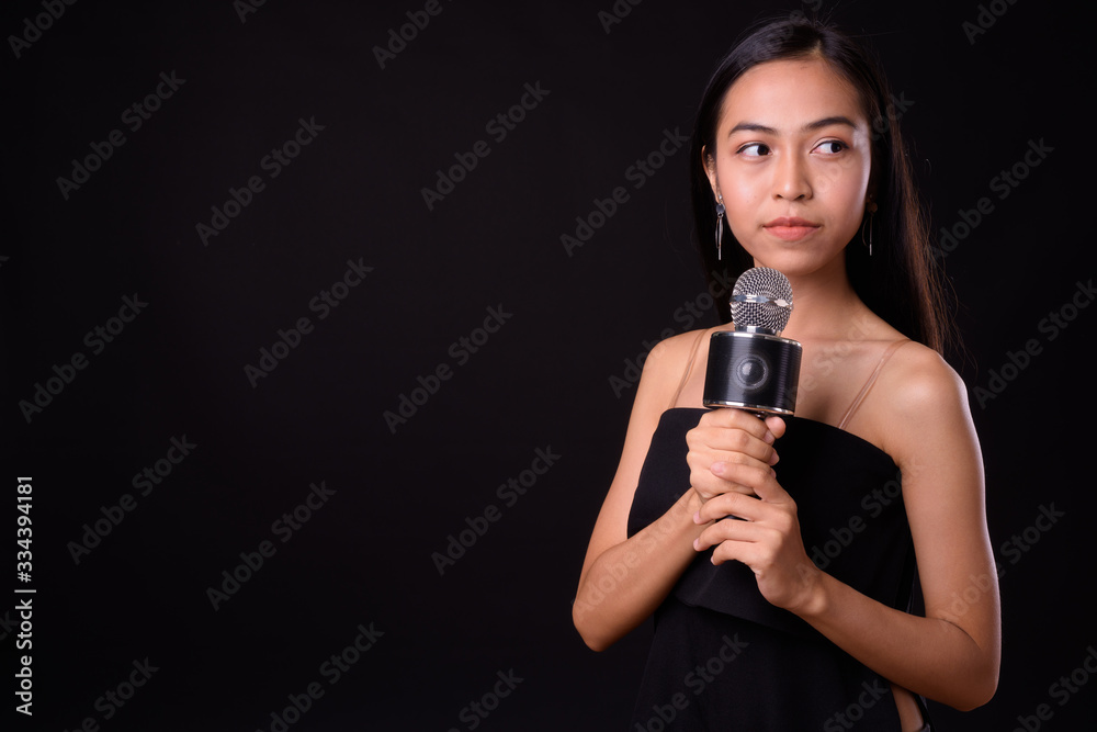 Portrait of young beautiful Asian woman using microphone Portrait of young beautiful Asian woman using microphone