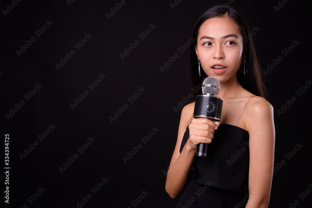 Portrait of young beautiful Asian woman using microphone Portrait of young beautiful Asian woman using microphone