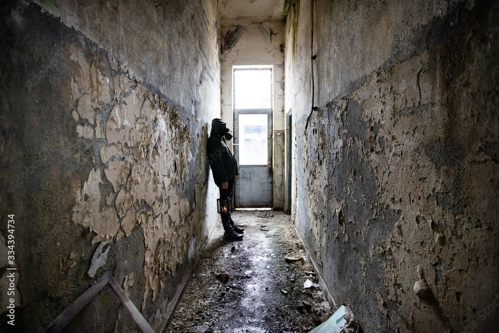 Dramatic portrait of a man wearing a gas mask in a ruined building.