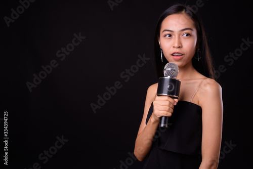 Portrait of young beautiful Asian woman using microphone