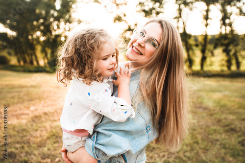Blonde mother with two cute daughters are walking and having fun outdoors. Stylish, casual clothes.