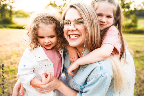 Blonde mother with two cute daughters are walking and having fun outdoors. Stylish, casual clothes.