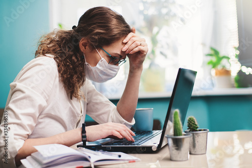 Distance learning. Online education or work. Woman in respiratory mask working at her office via laptop. Work process concept.