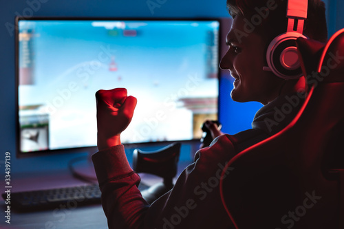 The smiling gamer with headphones playing video game on his personal computer photo