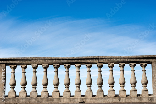 Billede på lærred Closeup of a concrete balustrade on a blue sky with clouds and copy space