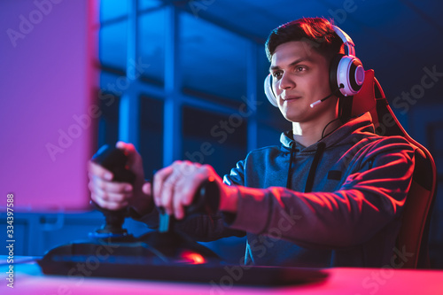 The gamer with headphones sitting and playing video games in the neon room photo