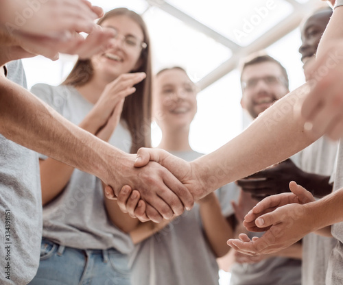 handshake of young people on the background of the applauding team