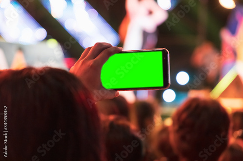 Hands of audience crowd people taking photo with mobile smart phone with green screen in party concert.