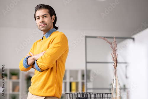 Young elegant businessman in yellow pullover and denim shirt looking at you