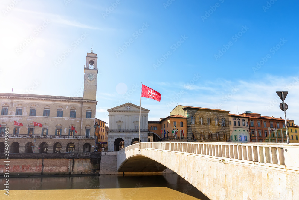 The central part of Pisa, the bridge over the Arno river, medieval houses and the bright sun