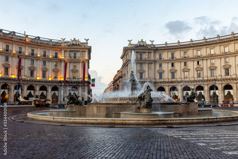 Republic Square in Rome, fountain and evening illumination of buildings, Italian flag in the background