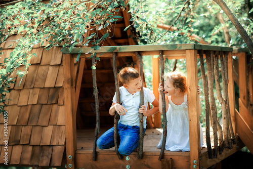 Little boy and girl playing in treehouse at forest park, Active kids on playground, Child enjoying activity in a climbing adventure park on summer sunny day. Ecological playground