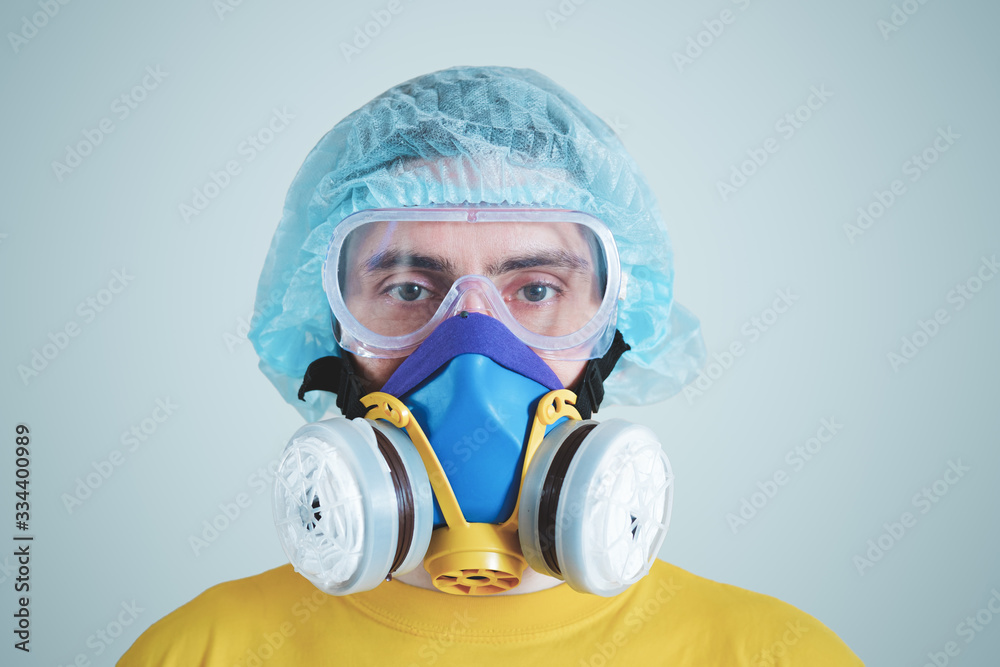 Man in protective face mask, eyeglasses and head protection. Medical personell, scientist or MD in work gear, concept of covid-19, virus, epidemic and vaccine development
