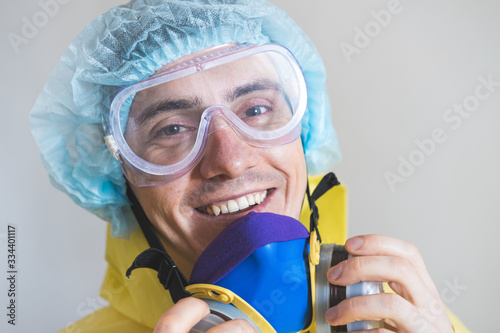 Portrait of a happy medical worker puts off protective gear after a shift. Concept of covid-19 epidemic, healthcare personell and overworking in hospitals photo