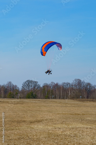 paraglider begins to take off over the field on a sunny day