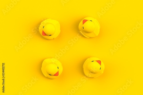 Close up of rubber ducks isolated. Bath toys on a yellow background. Top view with copy space. Summer wallpaper. 3d rendering.