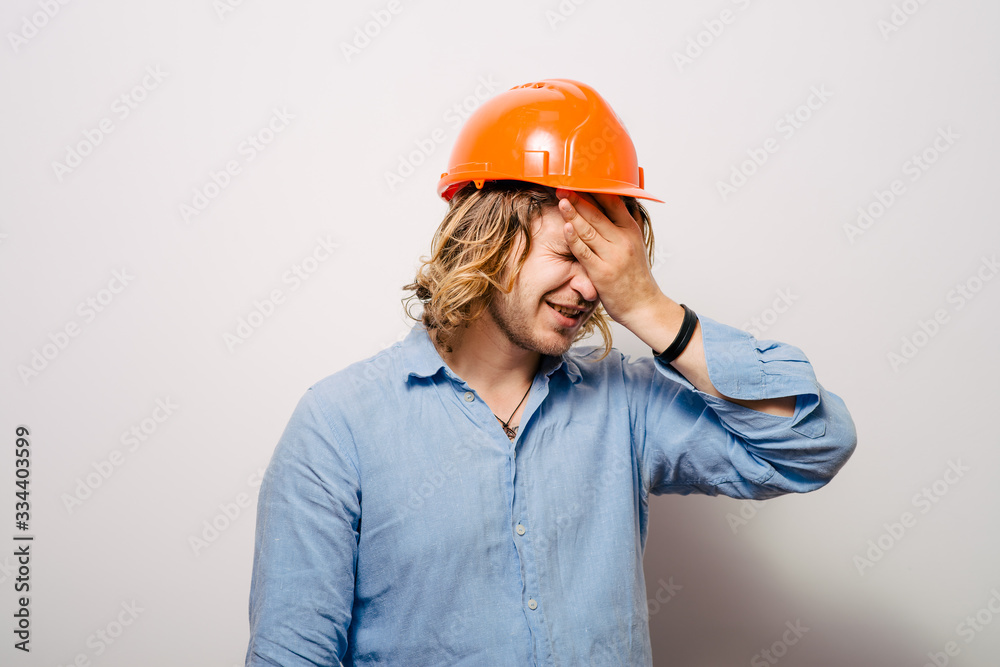 Tired young manual worker - builder, isolated on gray background, close-up studio shot Tired young manual worker - builder, isolated on gray background, close-up studio shot