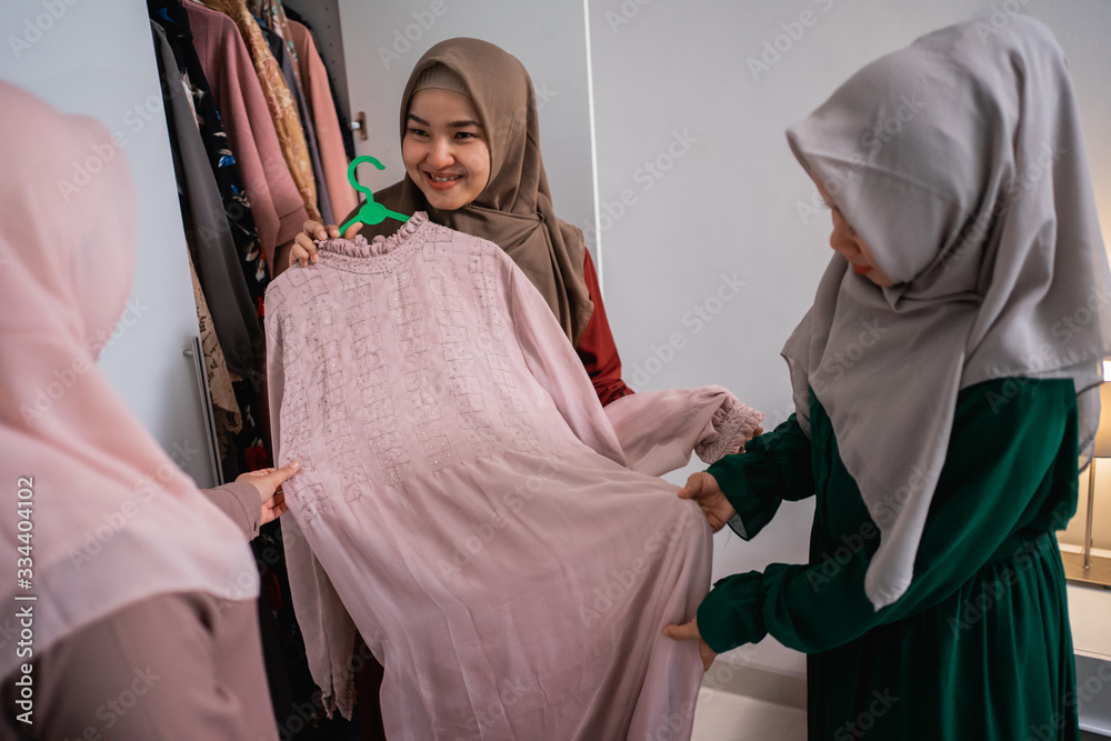 muslim woman friend picking up some dress from a wardrobe
