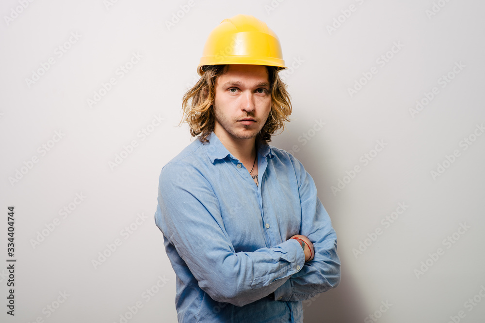 Handsome young man with protective helmet on his head and arms crossed Handsome young man with protective helmet on his head and arms crossed