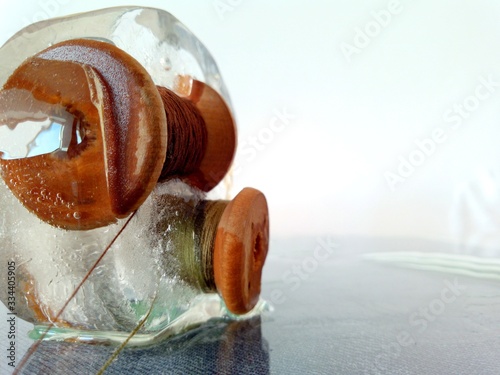 sewing reels frozen in ice on a glass surface and a light background in a creative macro photo