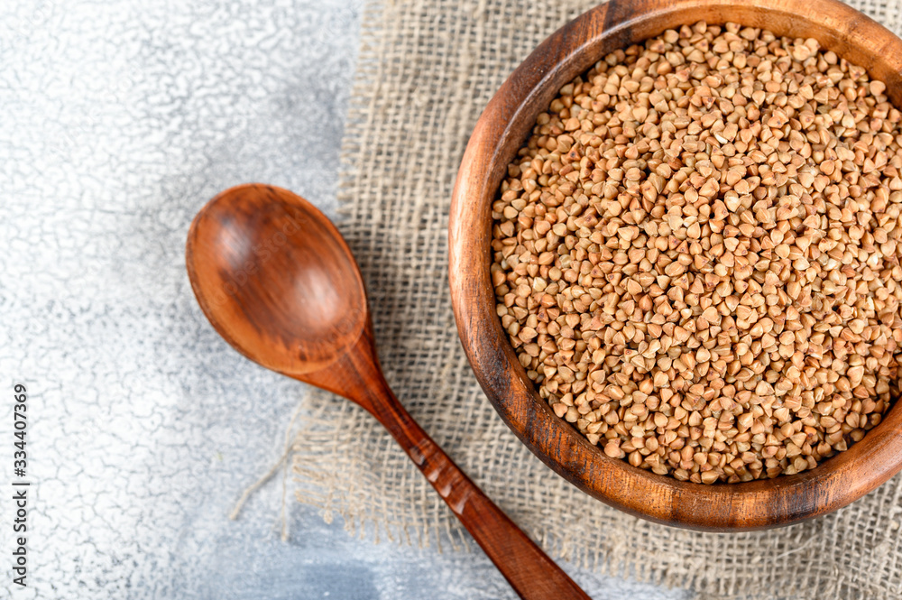 Buckwheats in a wood bowl on a sack cloth and light background. Buckwheats in a wood bowl on a sack cloth and light background.